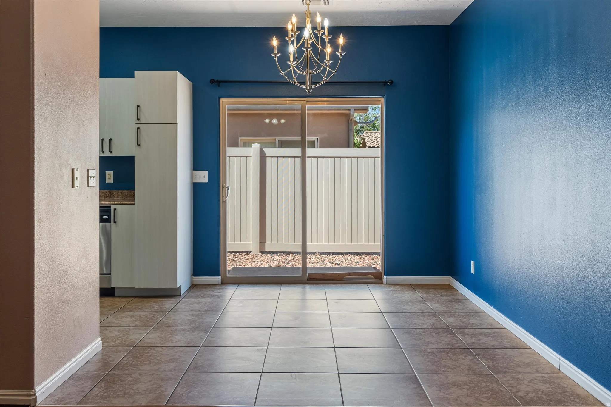 Ceramic tile flooring extends throughout this space featuring a chandelier and sliding glass patio doors