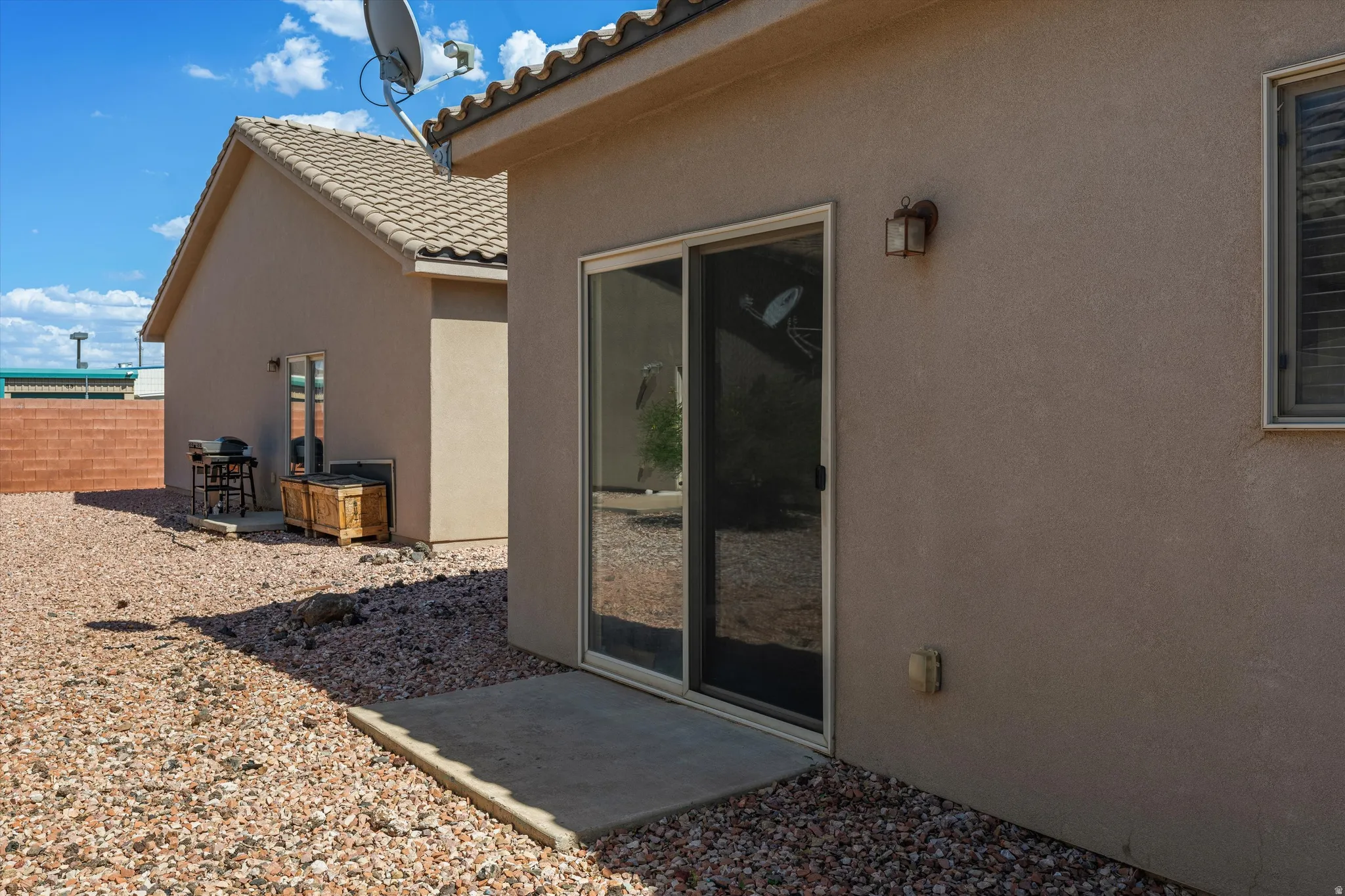 Stucco exterior with a sliding glass door and an exterior light fixture