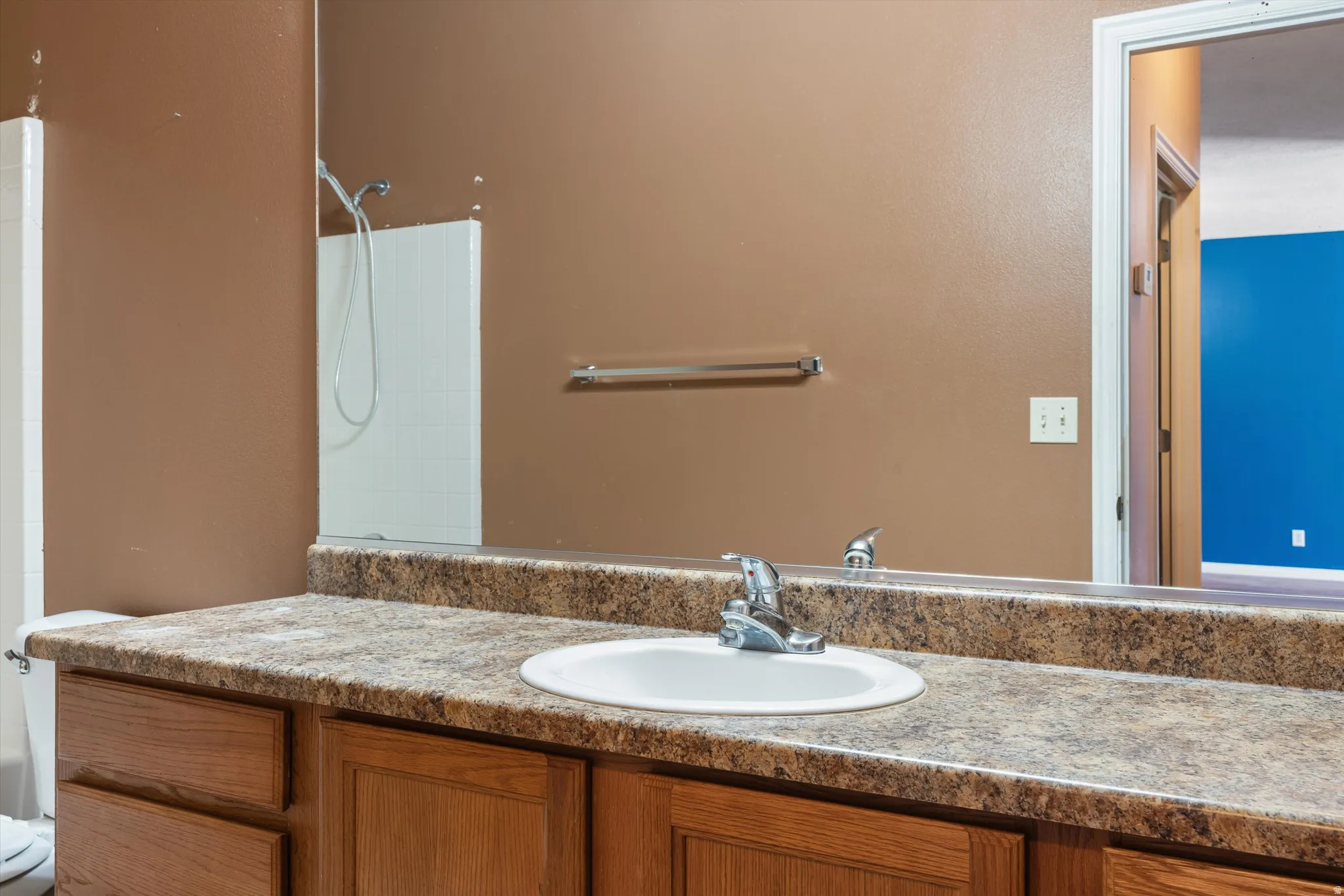 Bathroom vanity featuring a built-in sink, chrome faucet, and wood-finish cabinetry