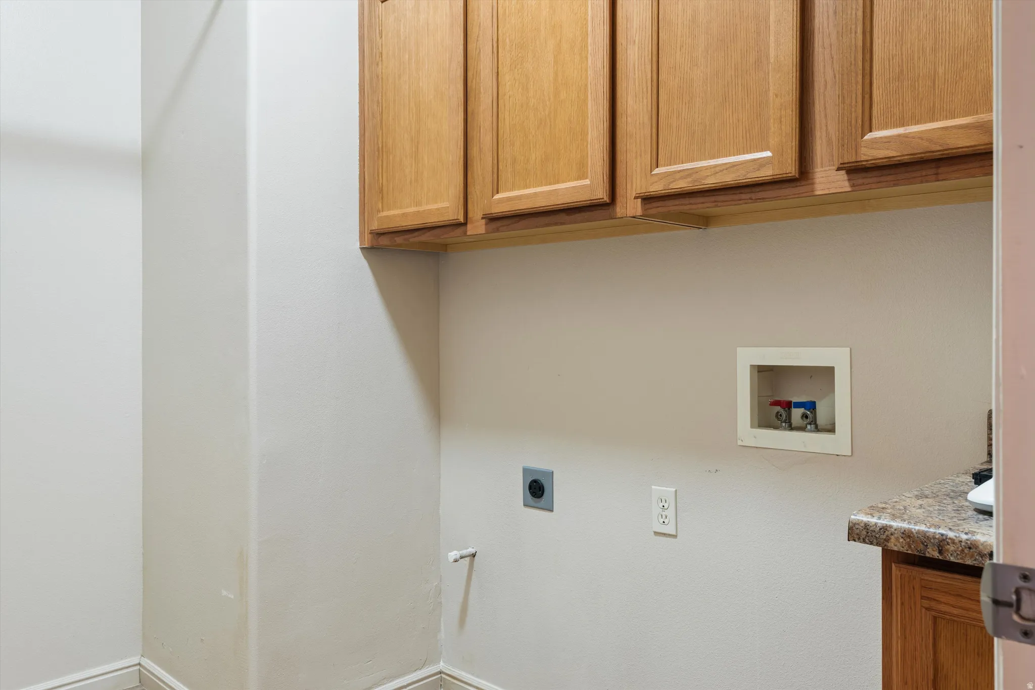 Utility area with wood-finish upper cabinetry and a laminate countertop