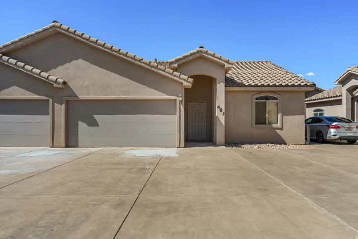 Stucco exterior with a tiled roof, featuring a two-car garage, an arched entry, and a window with an arched transom