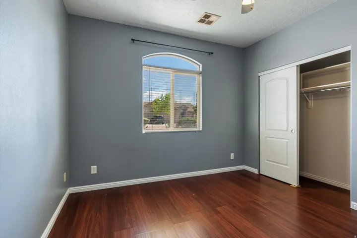Room featuring wood-finish flooring, an arched window with blinds, and neutral-toned walls