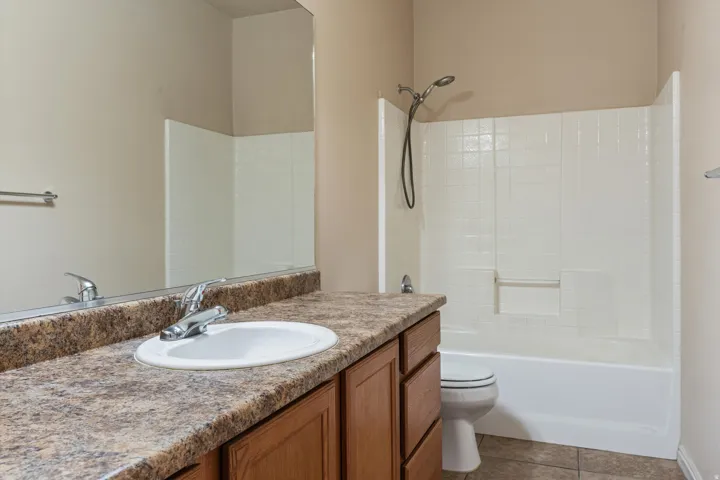 Full bathroom featuring a single vanity with wood cabinetry, a laminate countertop, and an integrated basin