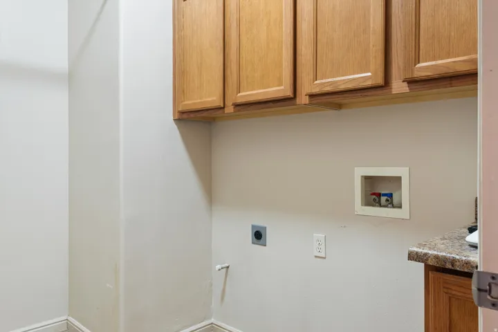 Utility area with wood-finish upper cabinetry and a laminate countertop