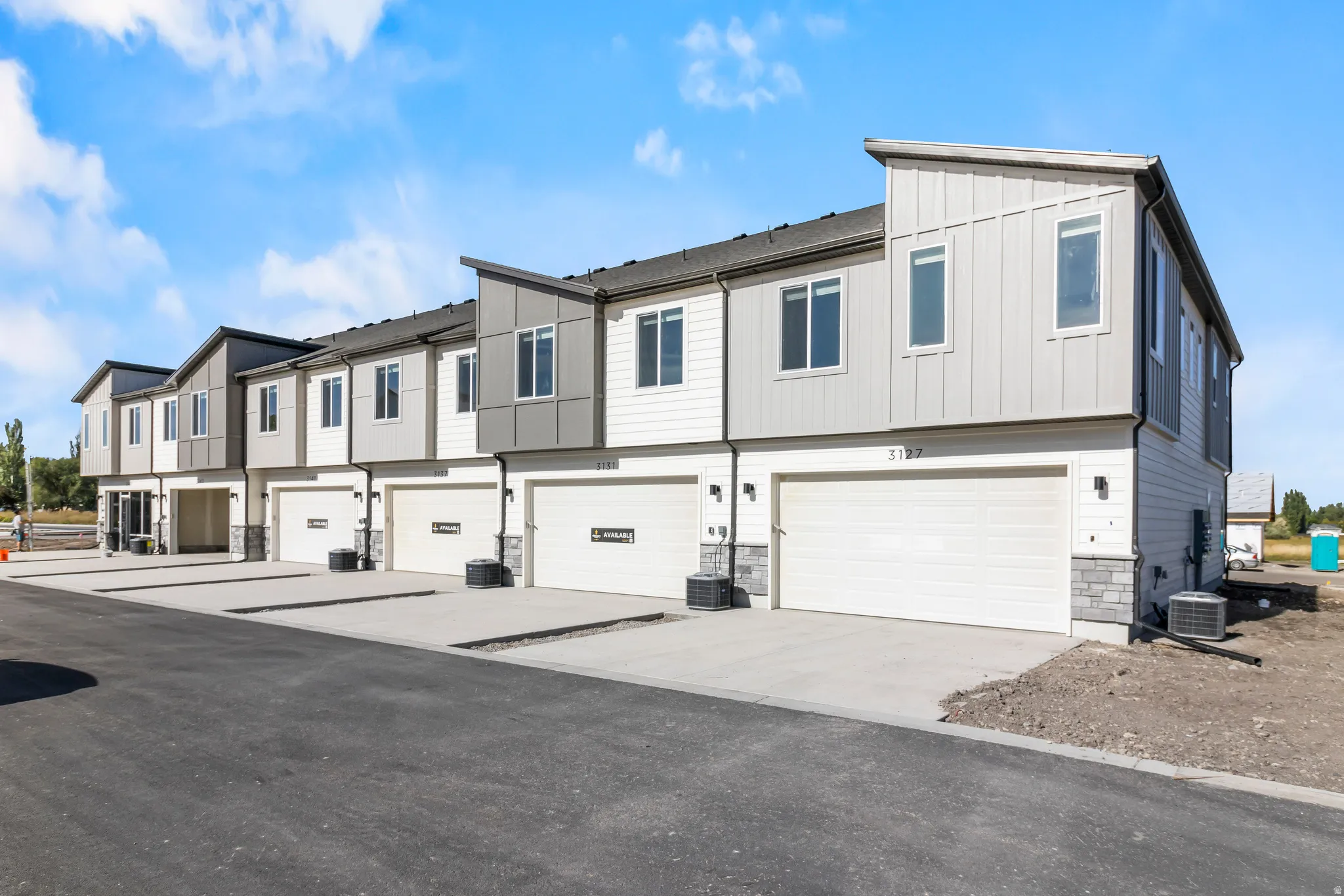 Contemporary townhome exteriors featuring vertical and horizontal siding, stone accents, and sloped rooflines