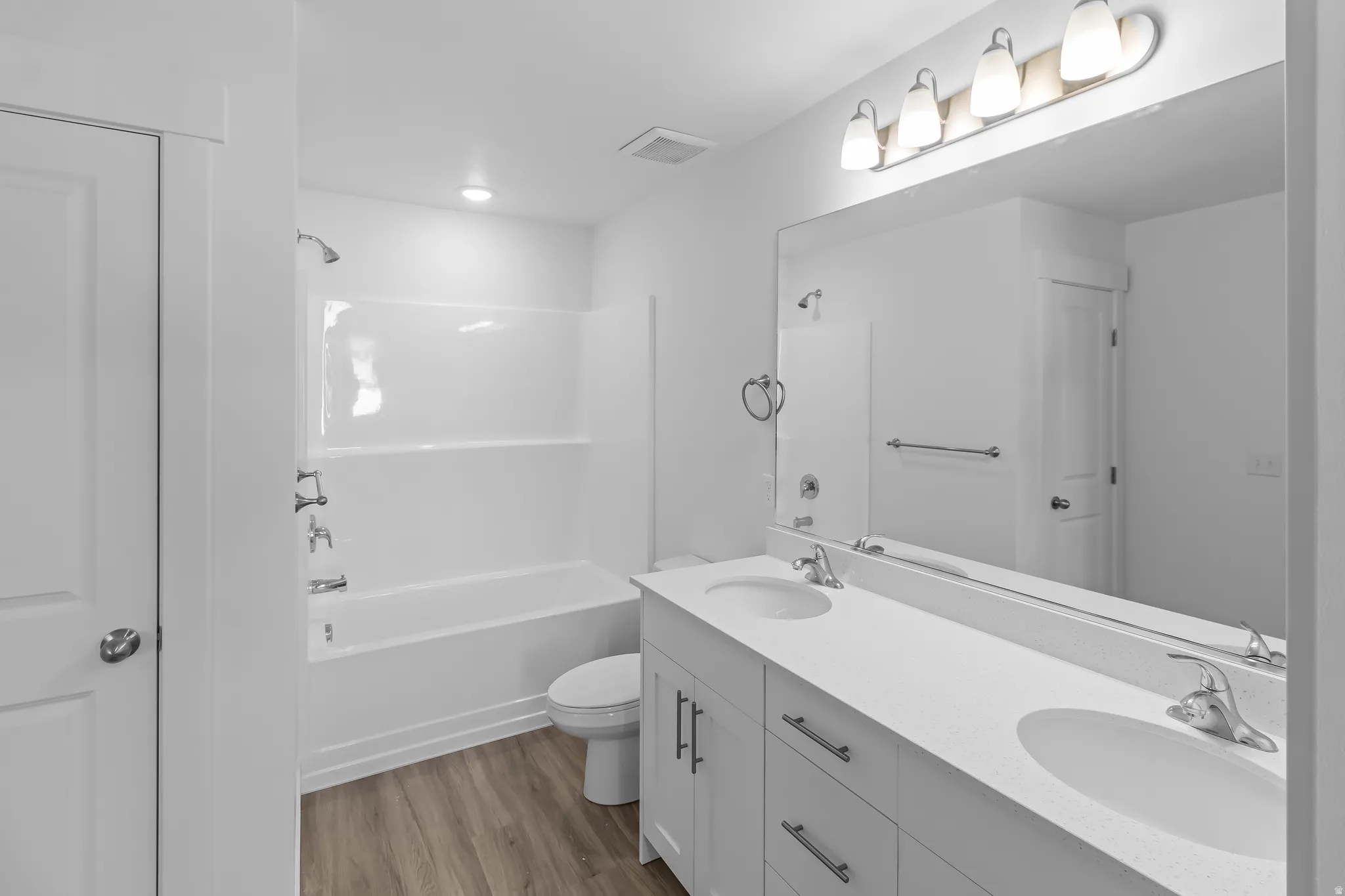 Bathroom featuring a dual-sink vanity with a light-toned countertop, white cabinetry, and brushed nickel hardware