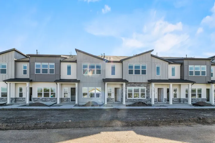 Modern townhome exteriors featuring varied siding textures, stone accents, multiple large windows, covered entryways, and contemporary rooflines