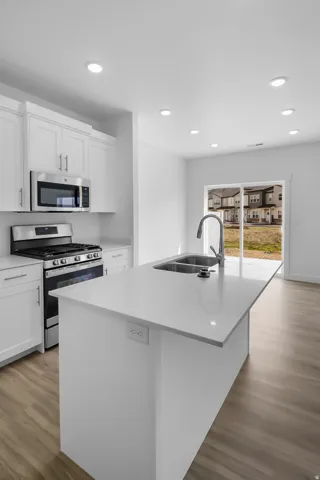 Modern kitchen island featuring a double-basin stainless steel sink with a high-arc faucet, white countertop, and integrated electrical outlets