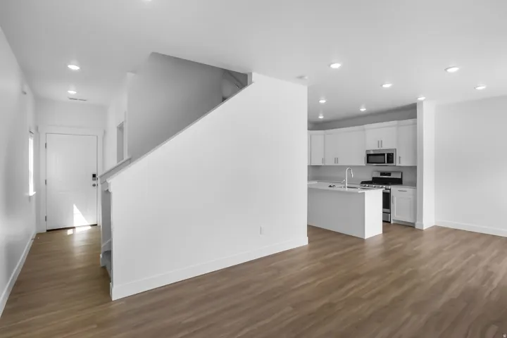 Open-concept living space featuring wood-finish flooring, recessed lighting, and a neutral color palette