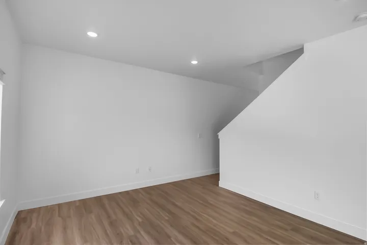 Open living area featuring wood-finish flooring, recessed lighting, white walls, and white baseboards
