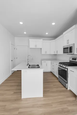 Bright kitchen featuring an island with a double basin sink and gooseneck faucet