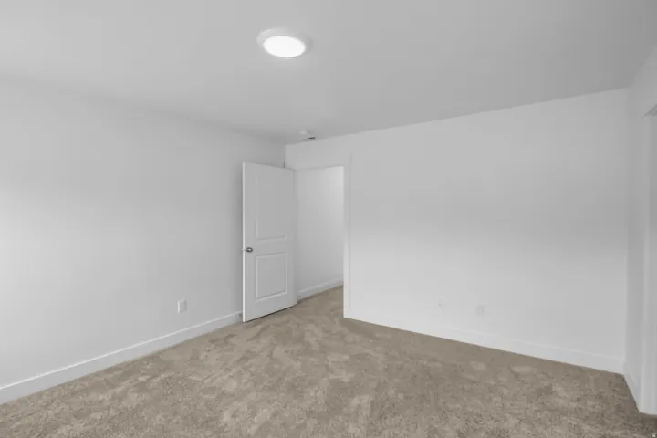Neutral-toned wall-to-wall carpeting complements bright white walls and trim