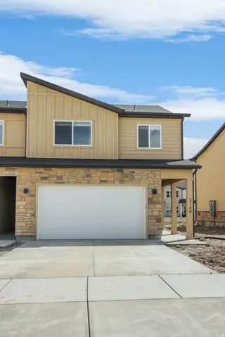 Modern exterior with a stone facade, a white garage door, and a covered entry