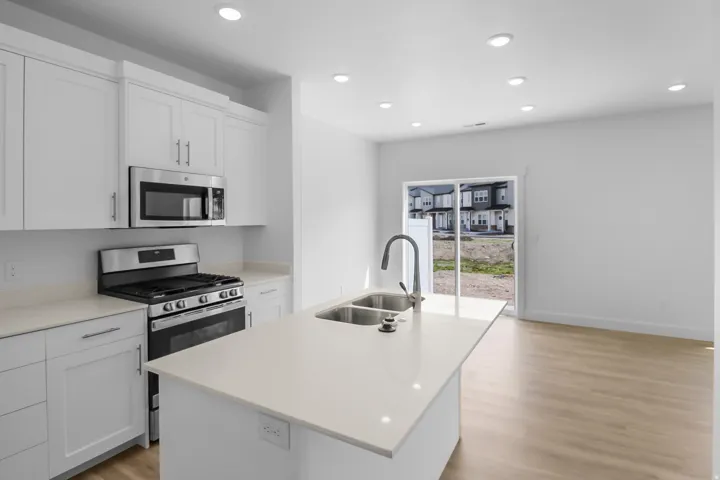 Modern kitchen featuring white cabinetry, stainless steel appliances, and a central island with an integrated double basin sink
