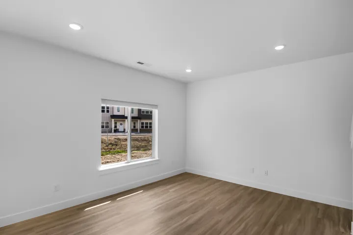 Bright interior room with wood-finish flooring, white walls, and recessed lighting