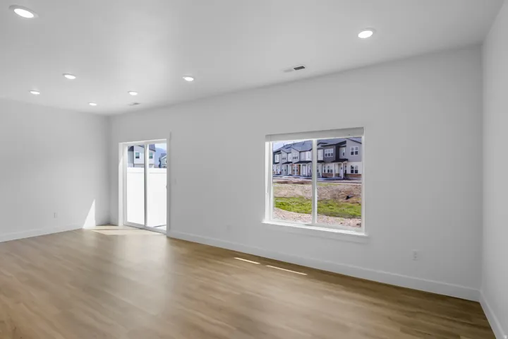 Spacious room featuring wood-finish flooring, recessed lighting, and white baseboards
