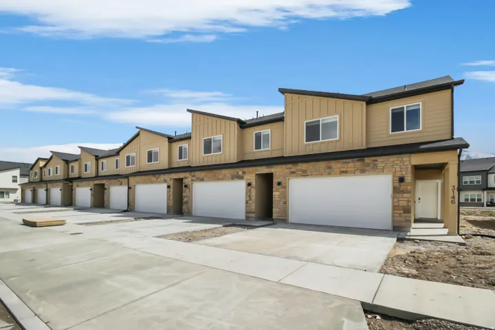 Modern townhome exteriors featuring horizontal siding, stone veneer accents, and white garage doors