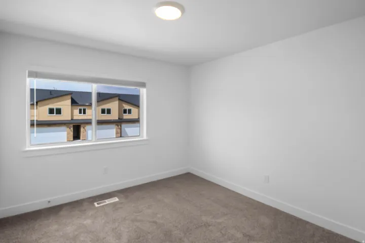 Bedroom featuring neutral carpeting, white walls, white baseboards, and a white window frame