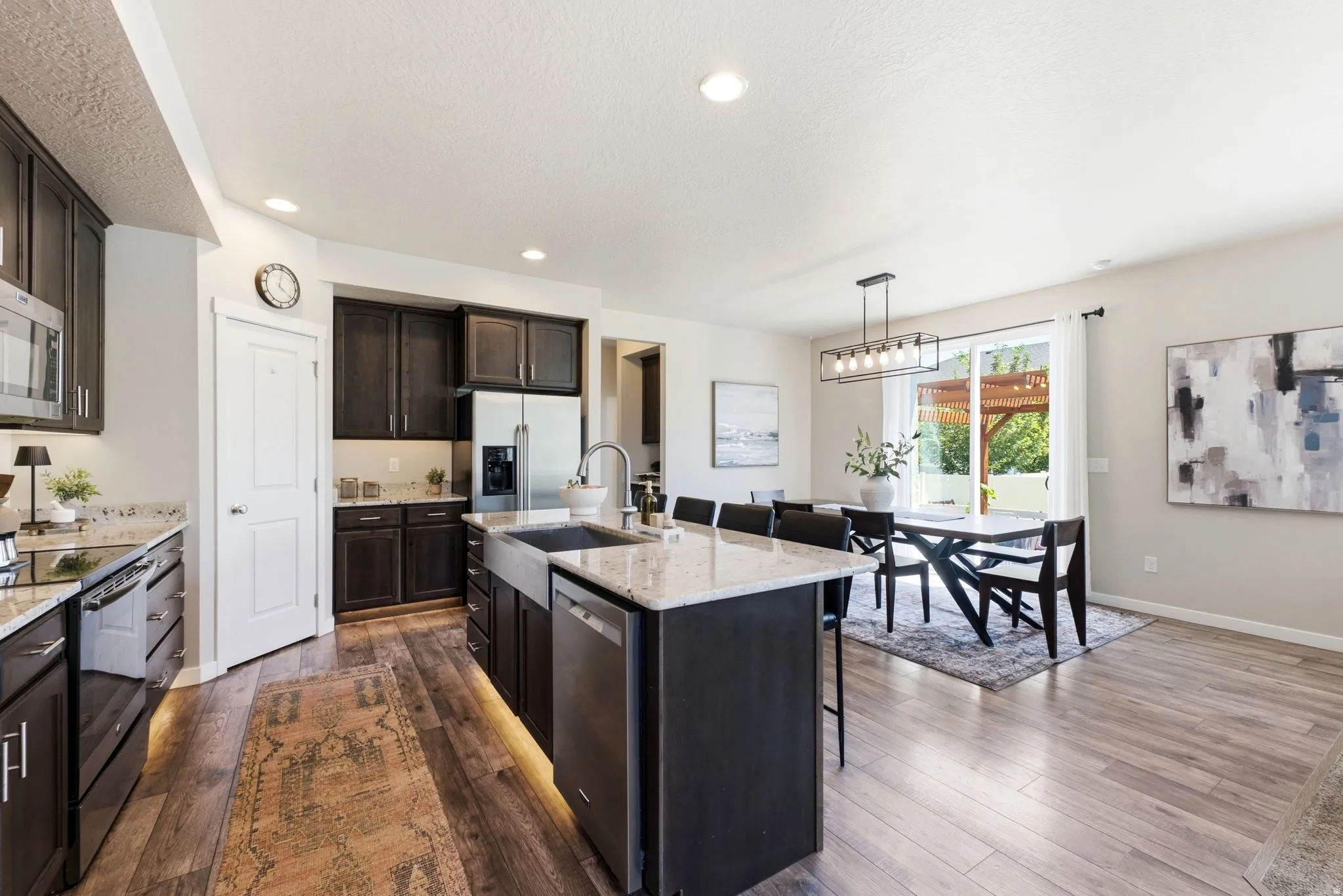 Open-concept kitchen and dining area featuring dark wood-finish cabinetry, stainless steel appliances, and light-colored countertops