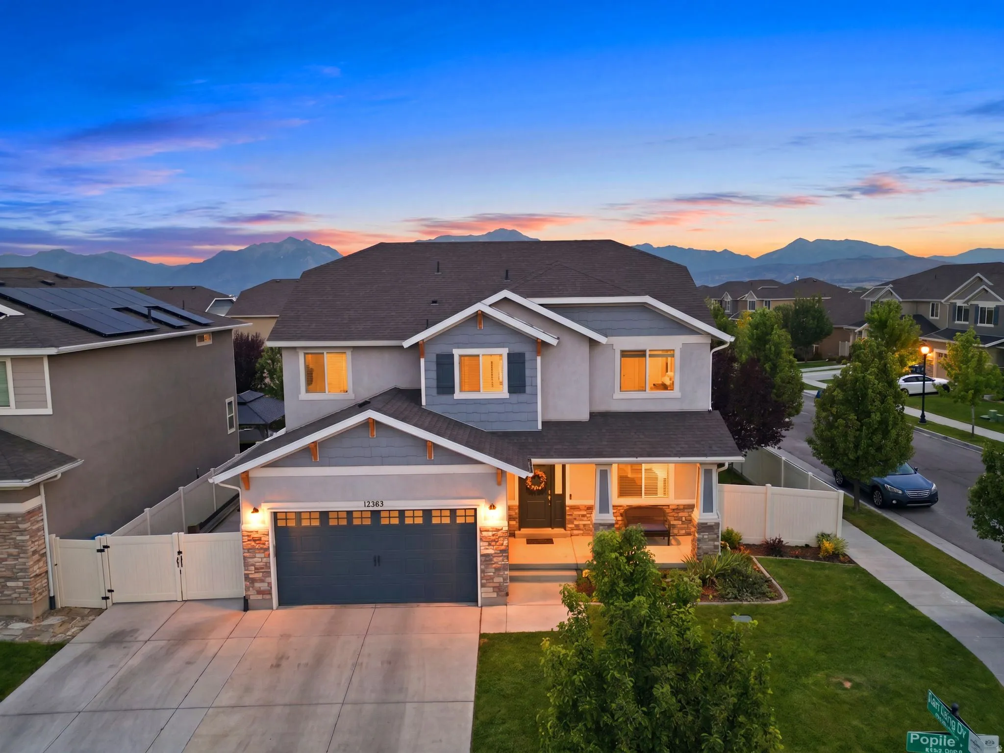 Two-story residence featuring a gray exterior with blue siding accents and stone veneer details