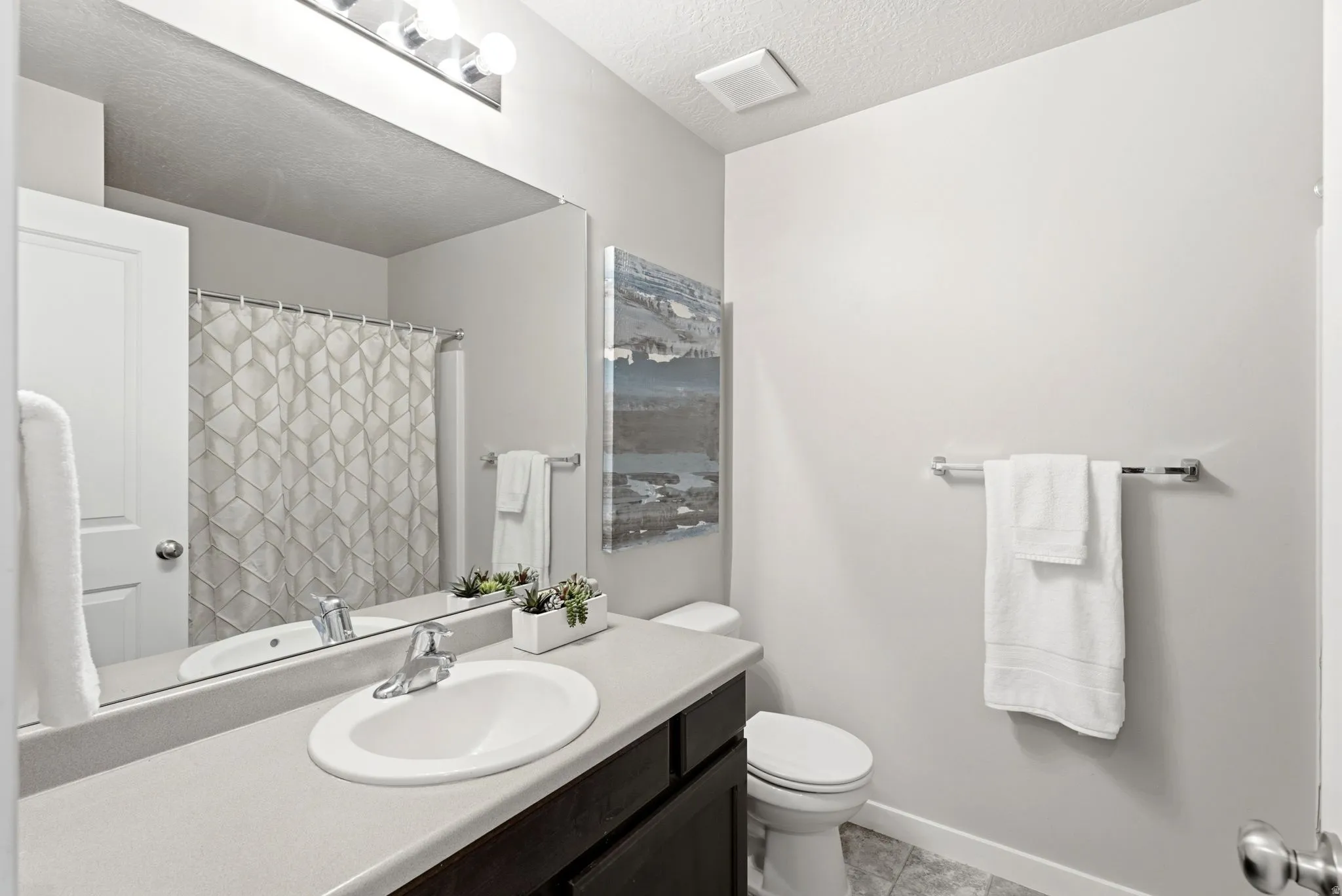 Full bathroom featuring a dark wood-finish vanity with a light gray countertop, an undermount sink, and a large wall-mounted mirror