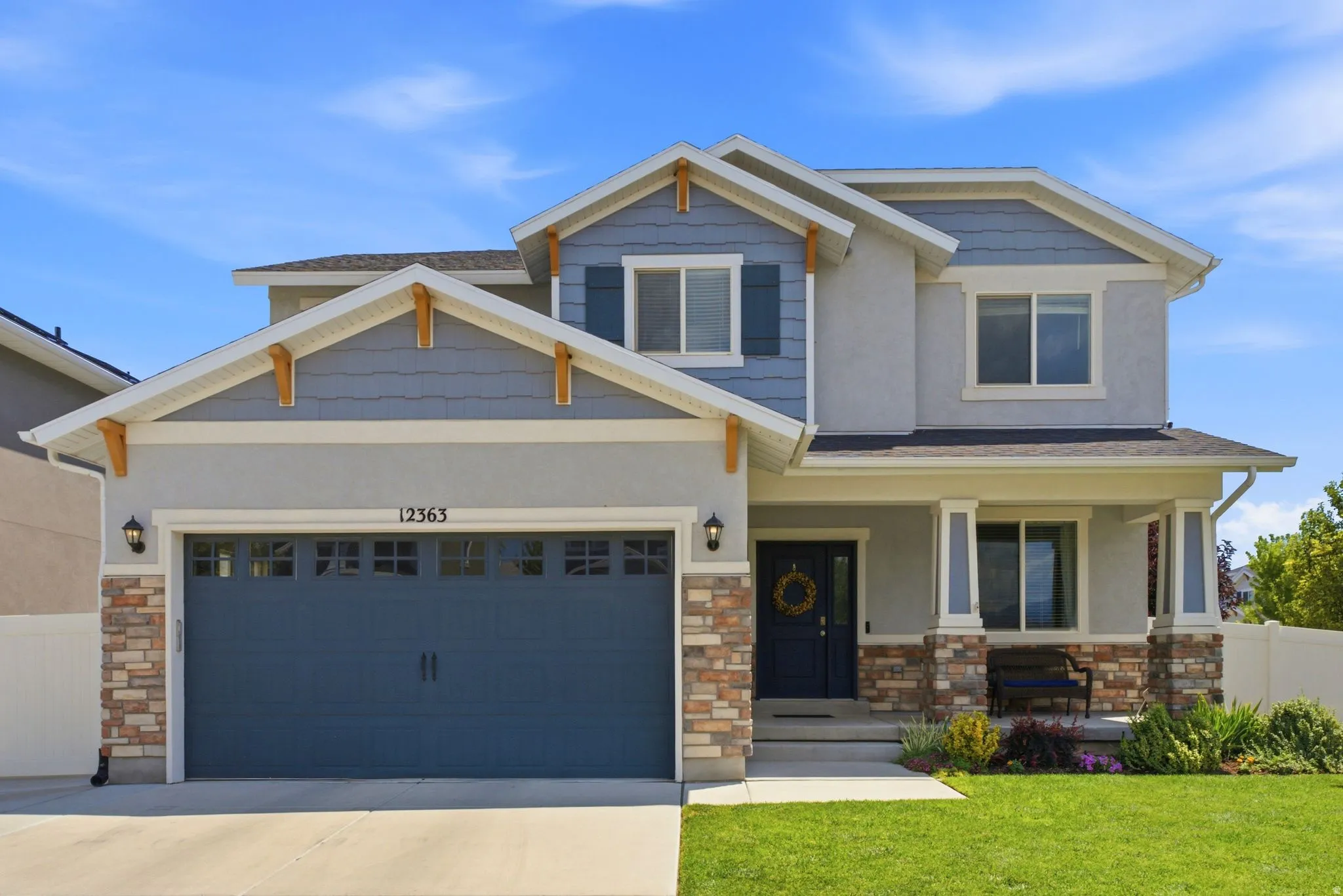 Contemporary two-story residence featuring a striking light gray stucco and blue siding exterior