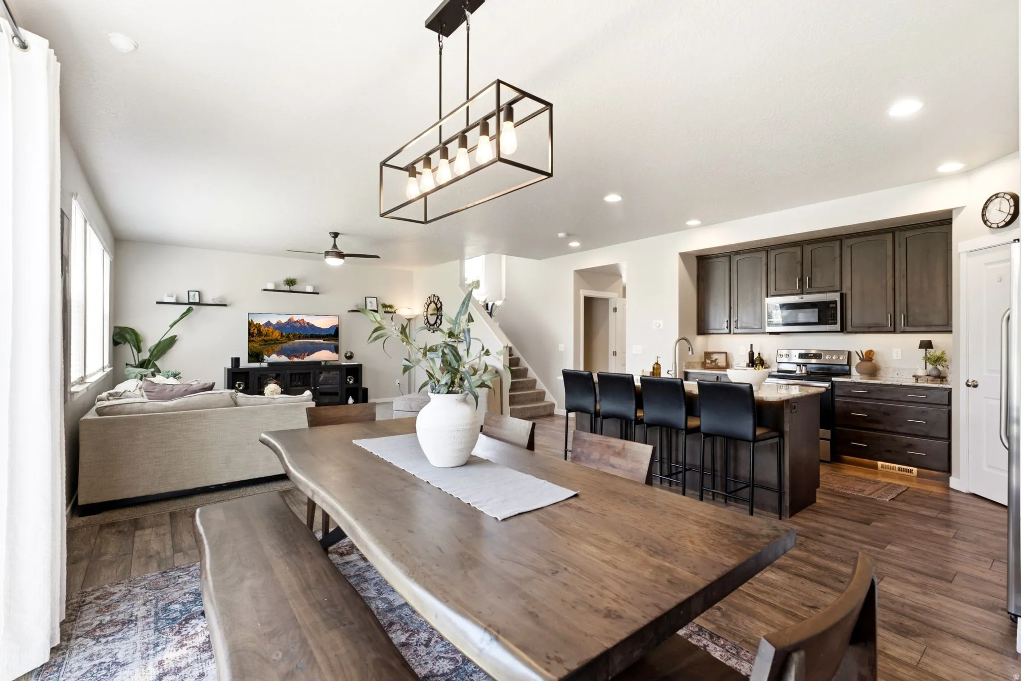 Open-concept living space featuring wood-finish flooring, a contemporary linear chandelier, and recessed lighting