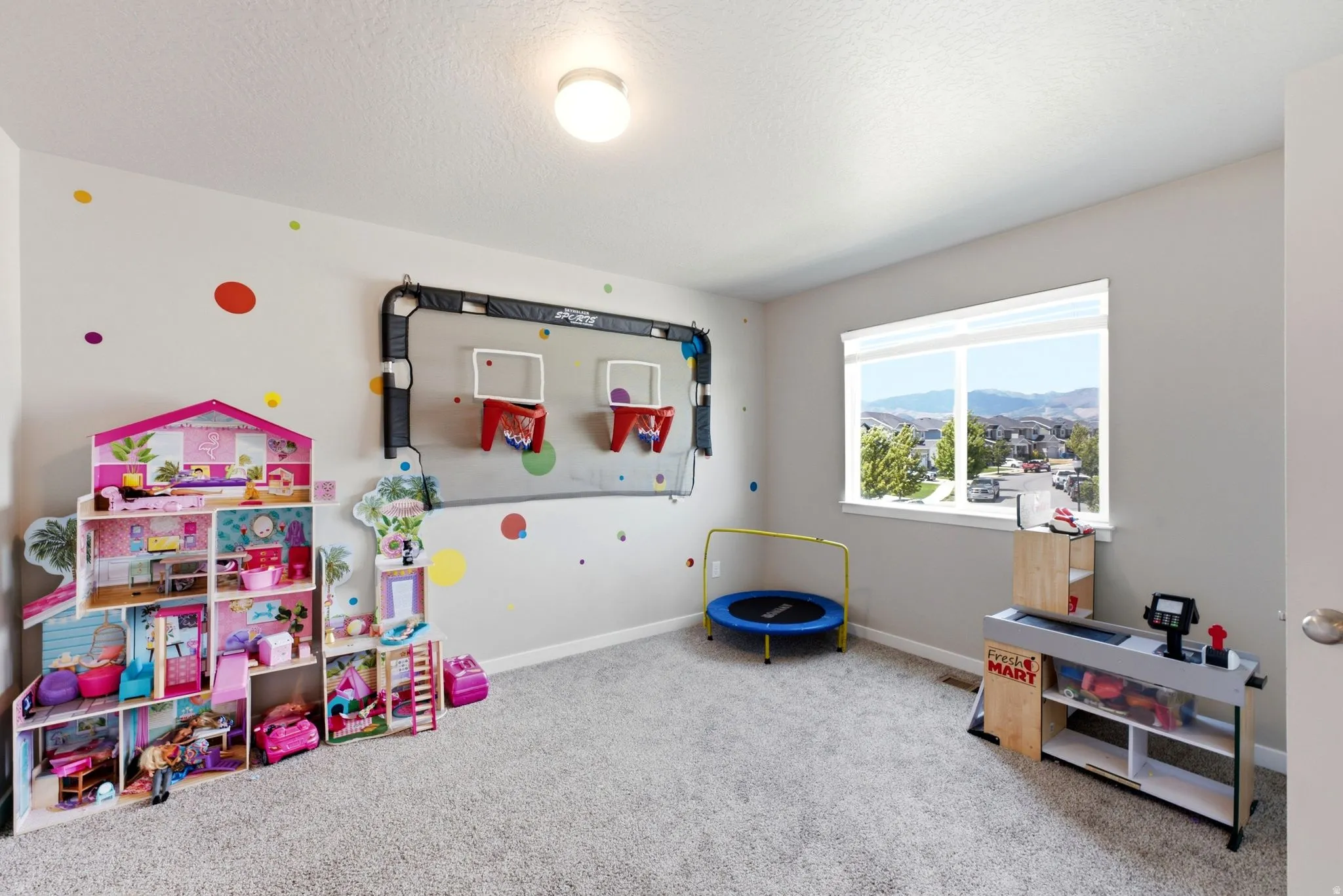 Spacious interior room featuring light gray walls, plush carpeting, and a large window with white blinds
