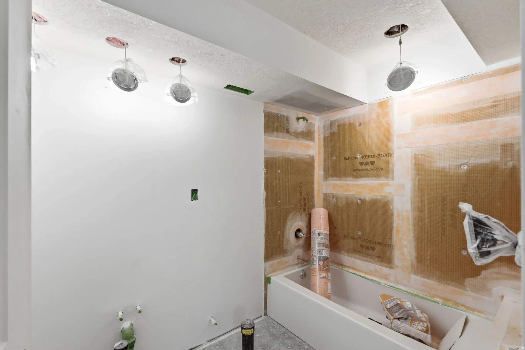 Bathroom in progress featuring a built-in tub, prepared walls for tile installation, recessed lighting, and a white ceiling