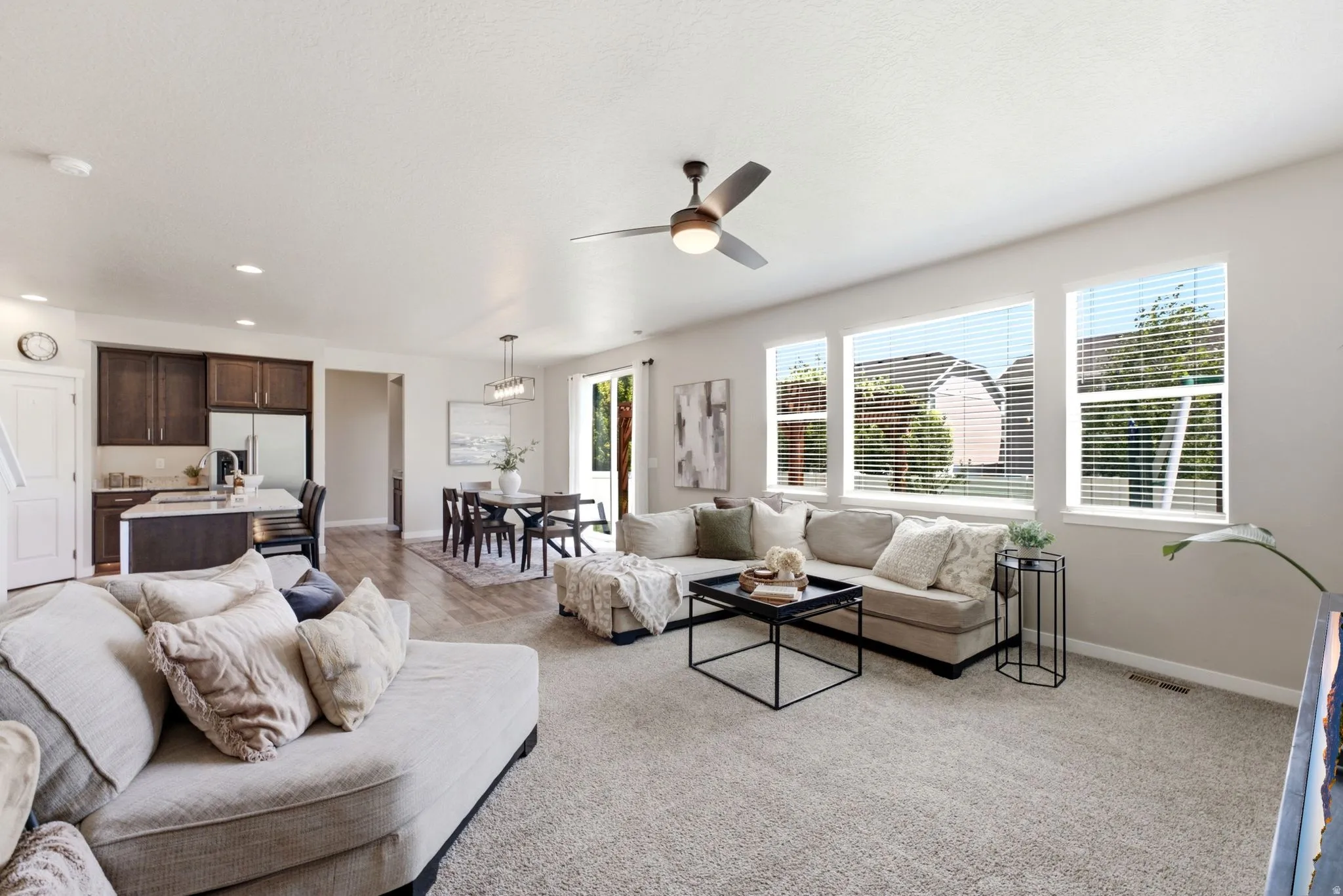 Open-concept living space featuring light-colored walls and grey carpet flooring