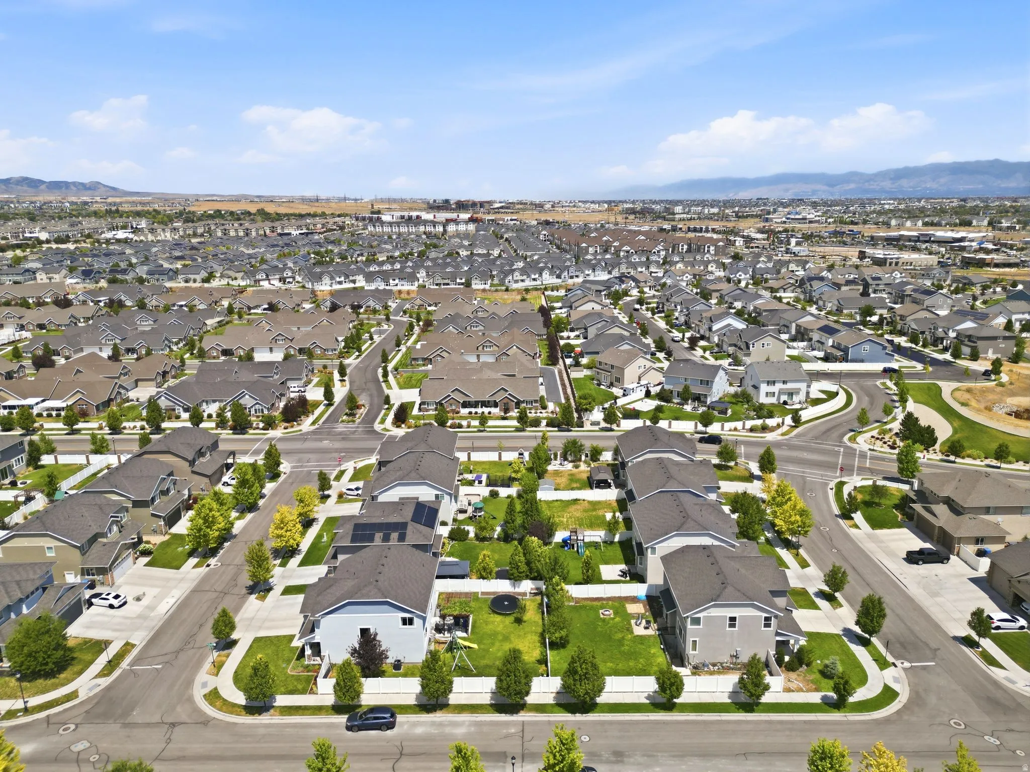 Expansive residential development featuring numerous single-family homes with gray shingle roofs, structured street layouts, and individual green lawns