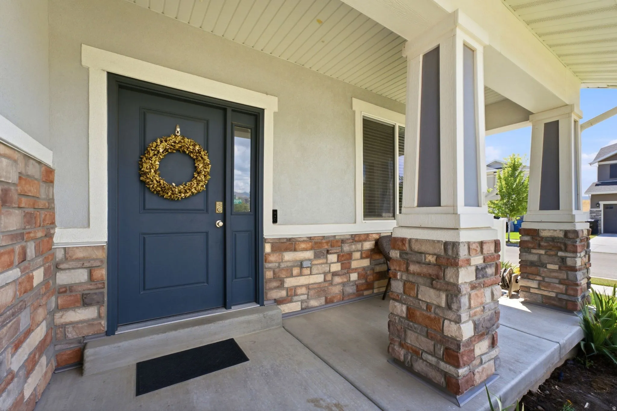 Welcoming front entrance featuring a paneled door, sidelight window, and stone veneer accents