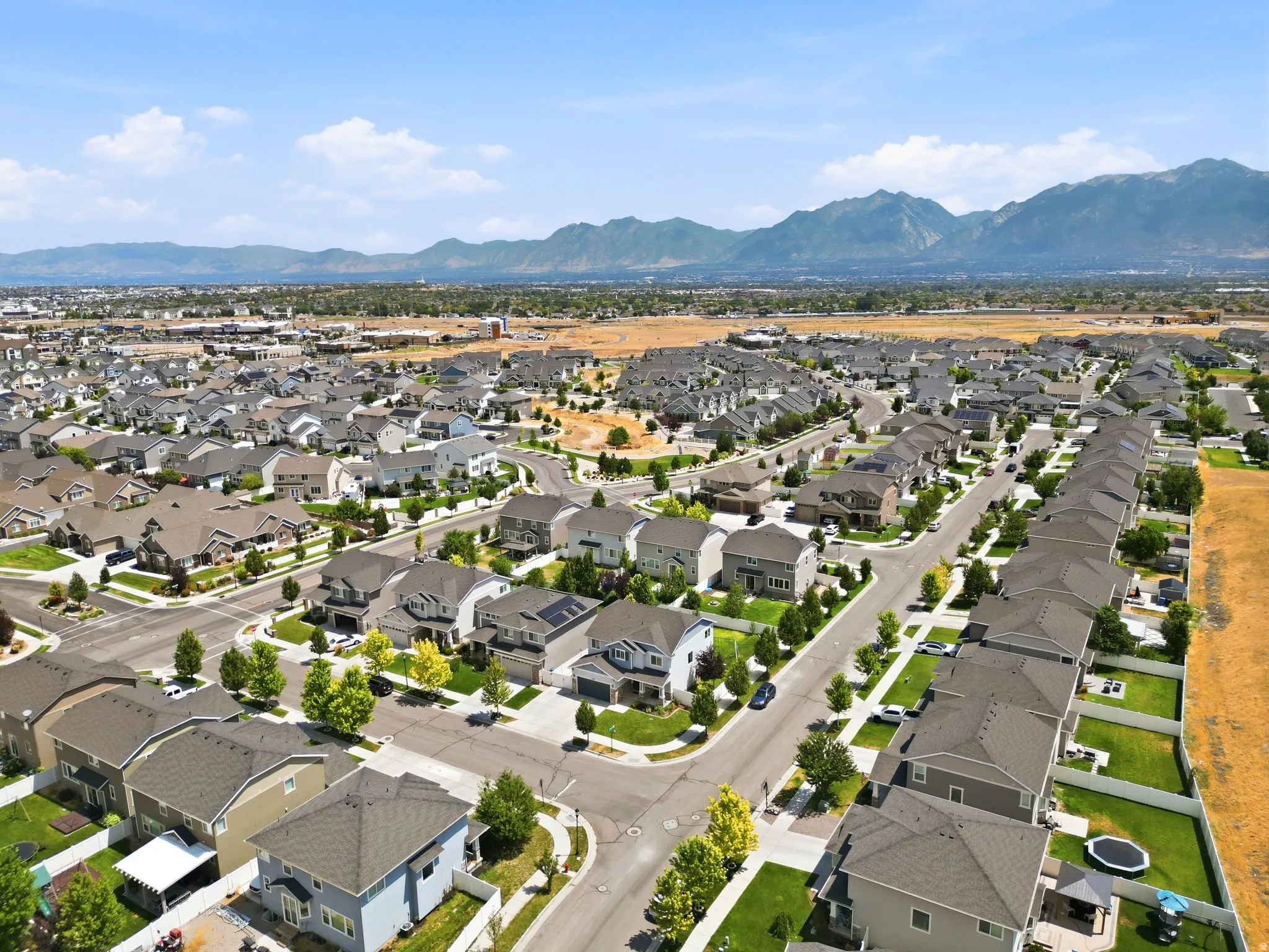 Residential neighborhood featuring a consistent architectural style, paved streets, varied landscaping, and a backdrop of distant mountains