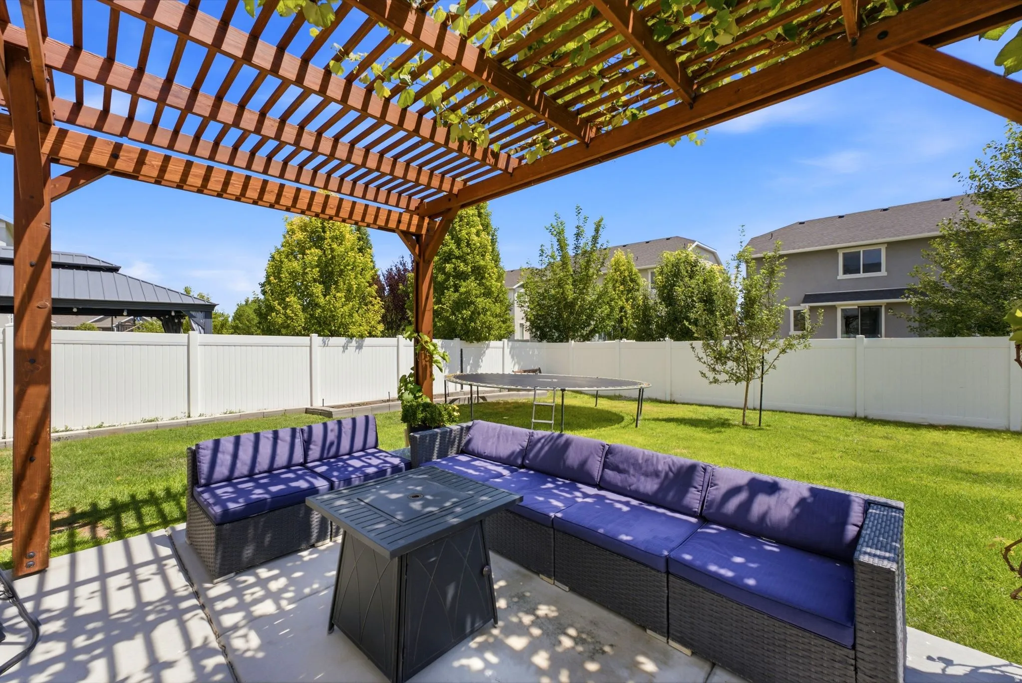 Concrete patio featuring a wooden pergola with climbing vines