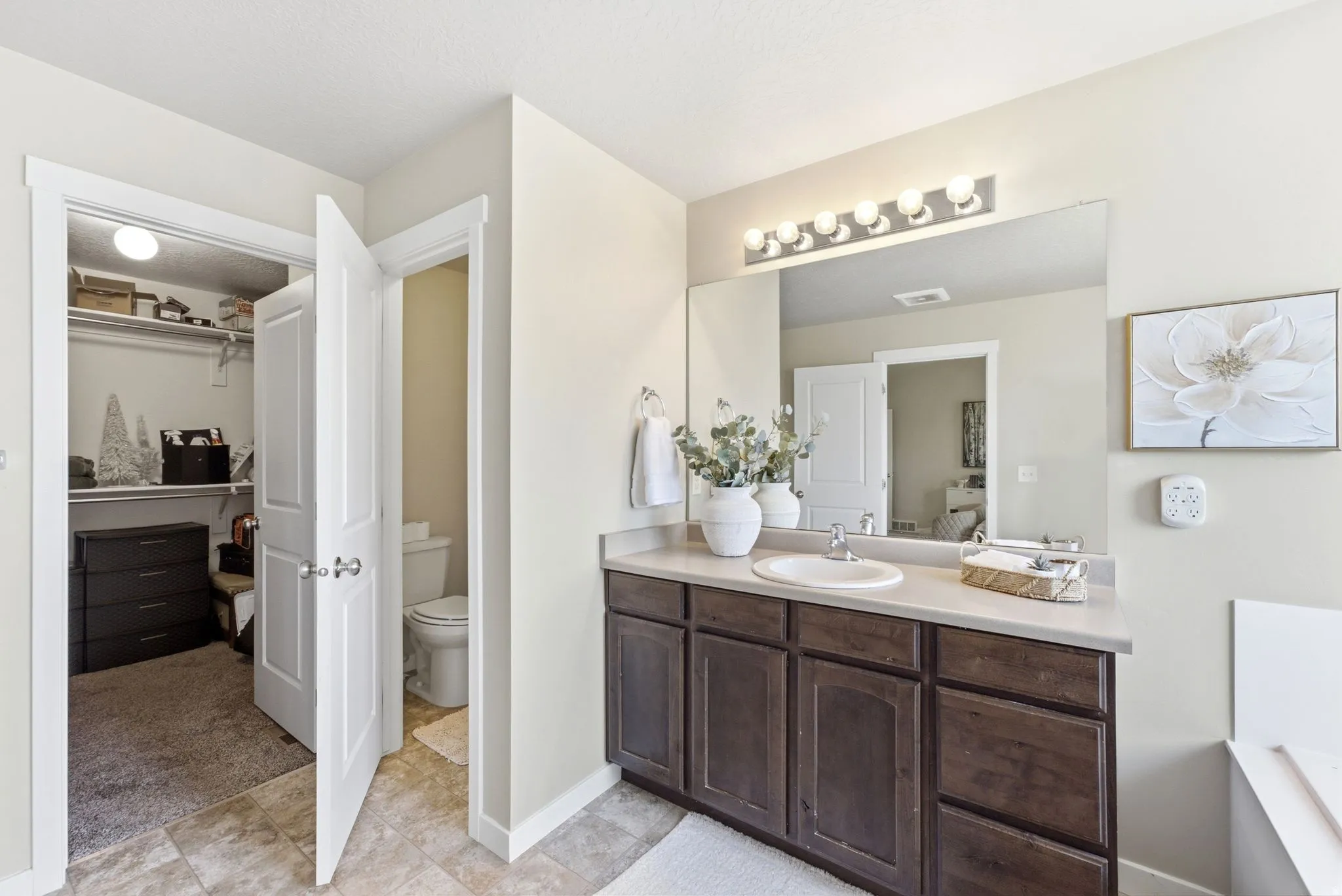 Bathroom vanity featuring a single basin sink, a light-toned countertop, and dark wood-finish cabinetry
