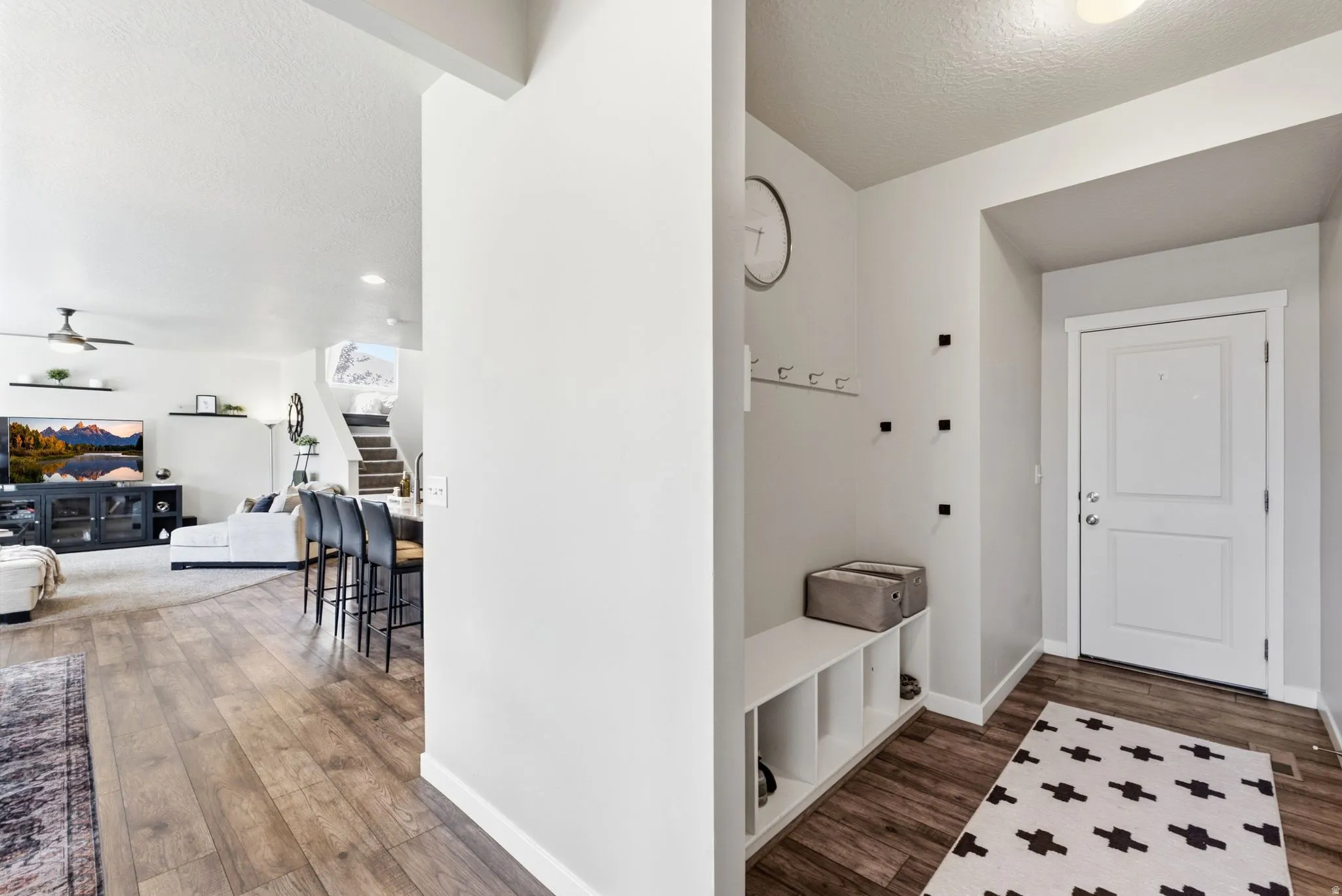 Entryway featuring wood-finish flooring, white door, and built-in storage bench with cubbies
