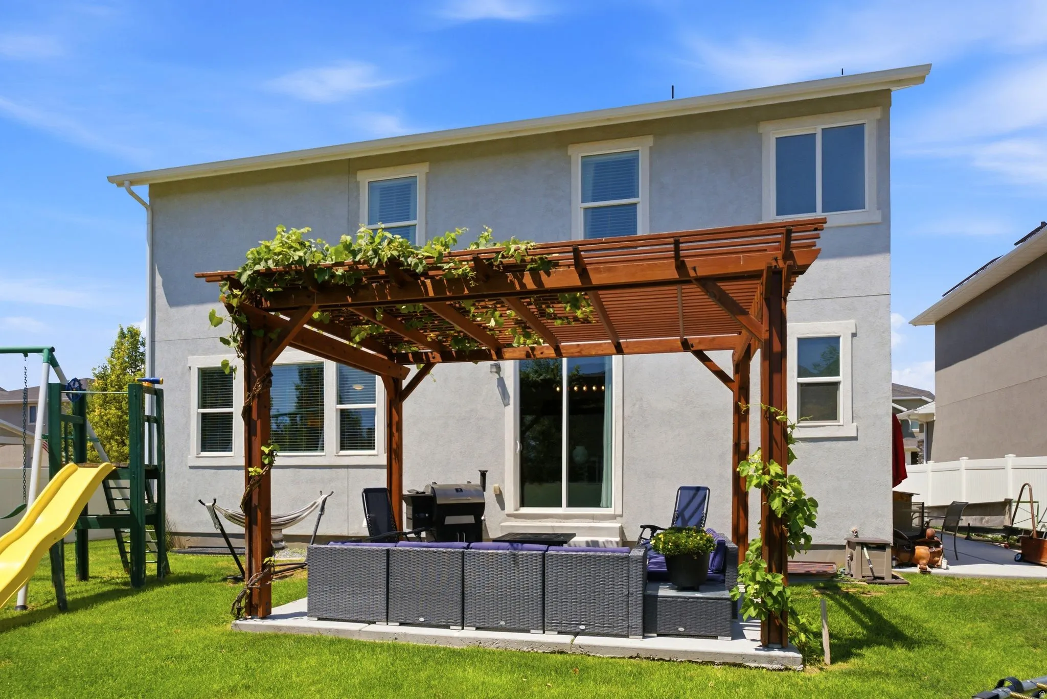 Expansive backyard featuring a lush lawn and a wood pergola with climbing greenery