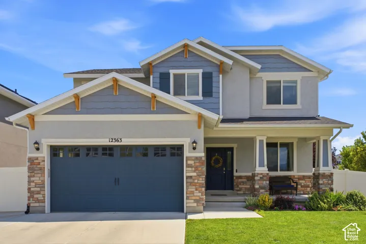 Modern two-story residence featuring a brick and stone exterior with complementary stucco accents, decorative timber gable detailing, and a two-car garage with paneled doors