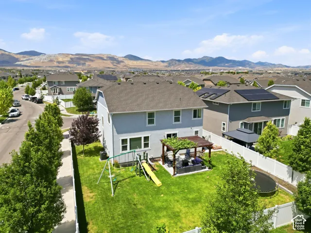 Expansive backyard with a manicured lawn, white vinyl fencing, and a dedicated patio area featuring a wooden pergola