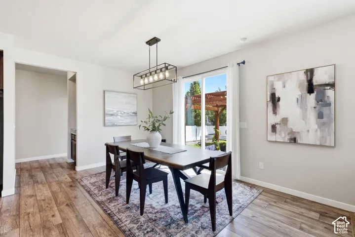 Spacious dining area featuring wood-finish flooring, a modern linear chandelier, and a sliding glass door to the exterior