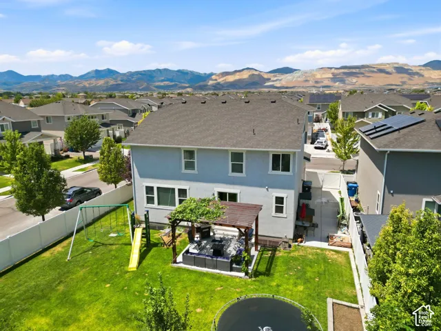 Expansive backyard featuring a lush lawn, a white privacy fence, and a pergola-covered patio area