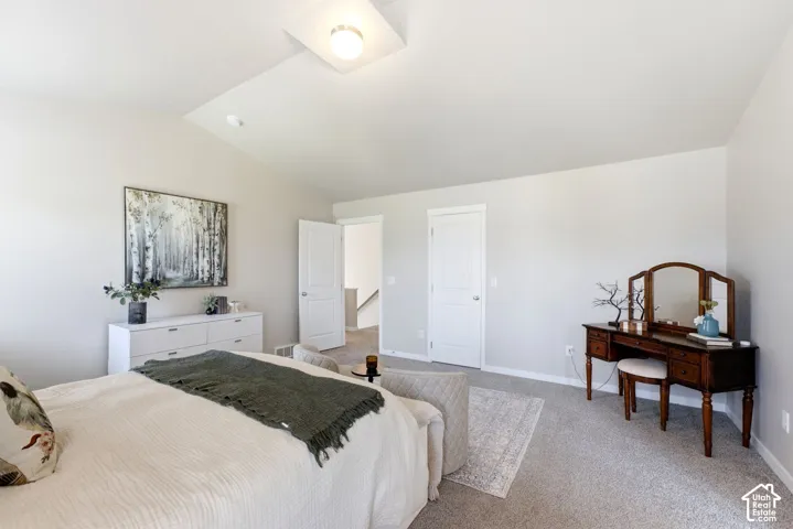 Vaulted ceiling with an attached light fixture, light gray carpet, and white trim molding