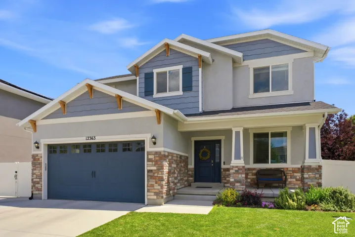 Stone veneer accents, horizontal siding, wood corbels, covered porch entry, and a two-car garage