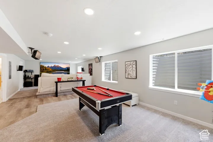 Recessed lighting, wood-finish flooring, two large windows, white trim, and a projector screen