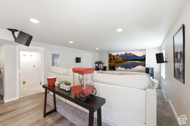 Recessed ceiling lighting, wall-mounted speakers, large projection screen, and wood-finish flooring