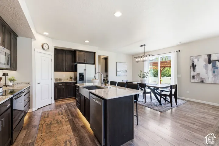 Modern kitchen featuring dark wood cabinetry, light-toned countertops, and wood-finish flooring