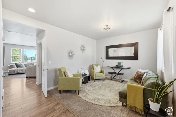 Light gray wall paint, recessed ceiling lighting, light wood-finish flooring, and a large window with sheer draperies
