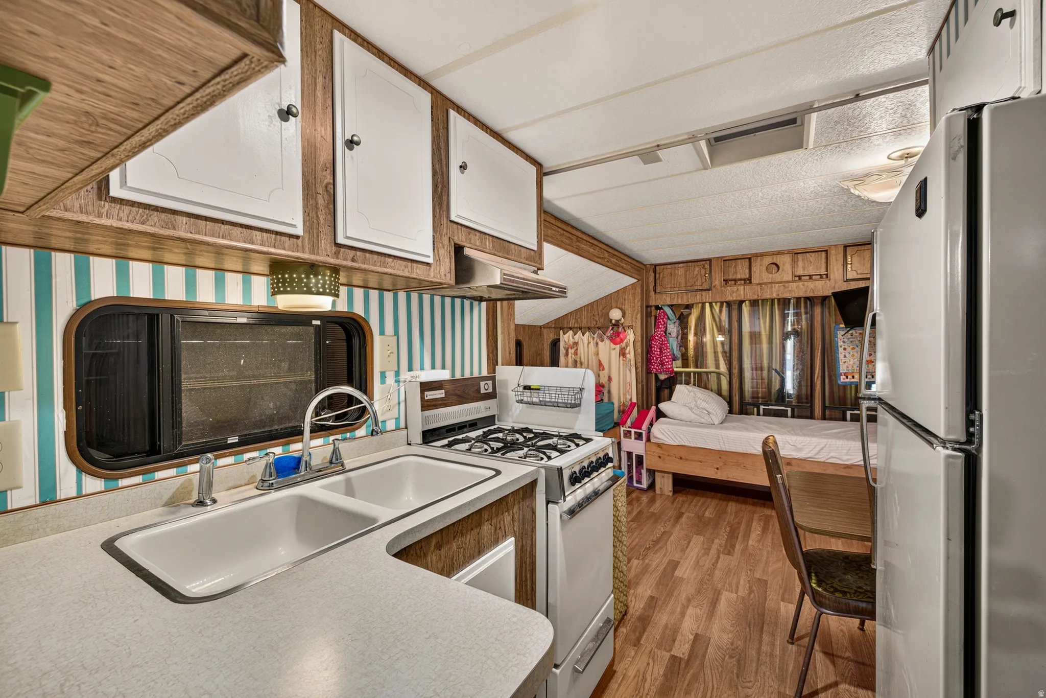 Full kitchen featuring a dual-basin sink, a four-burner gas range, white cabinetry, and wood-finish flooring