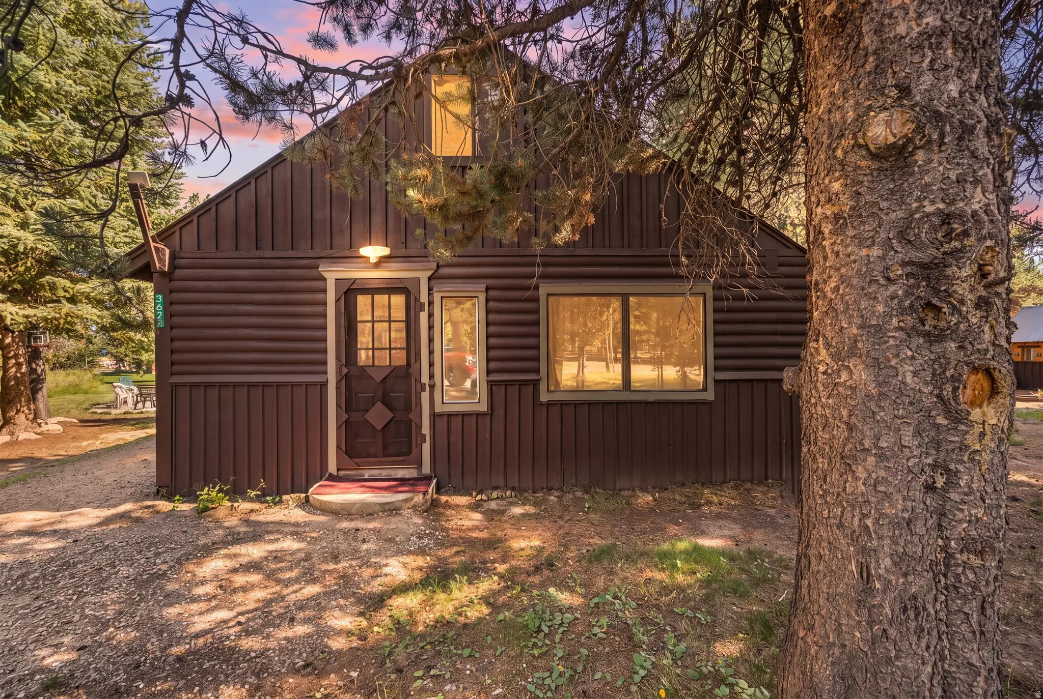 Rustic cabin exterior featuring dark wood-finish siding, a gabled roofline, and multiple windows