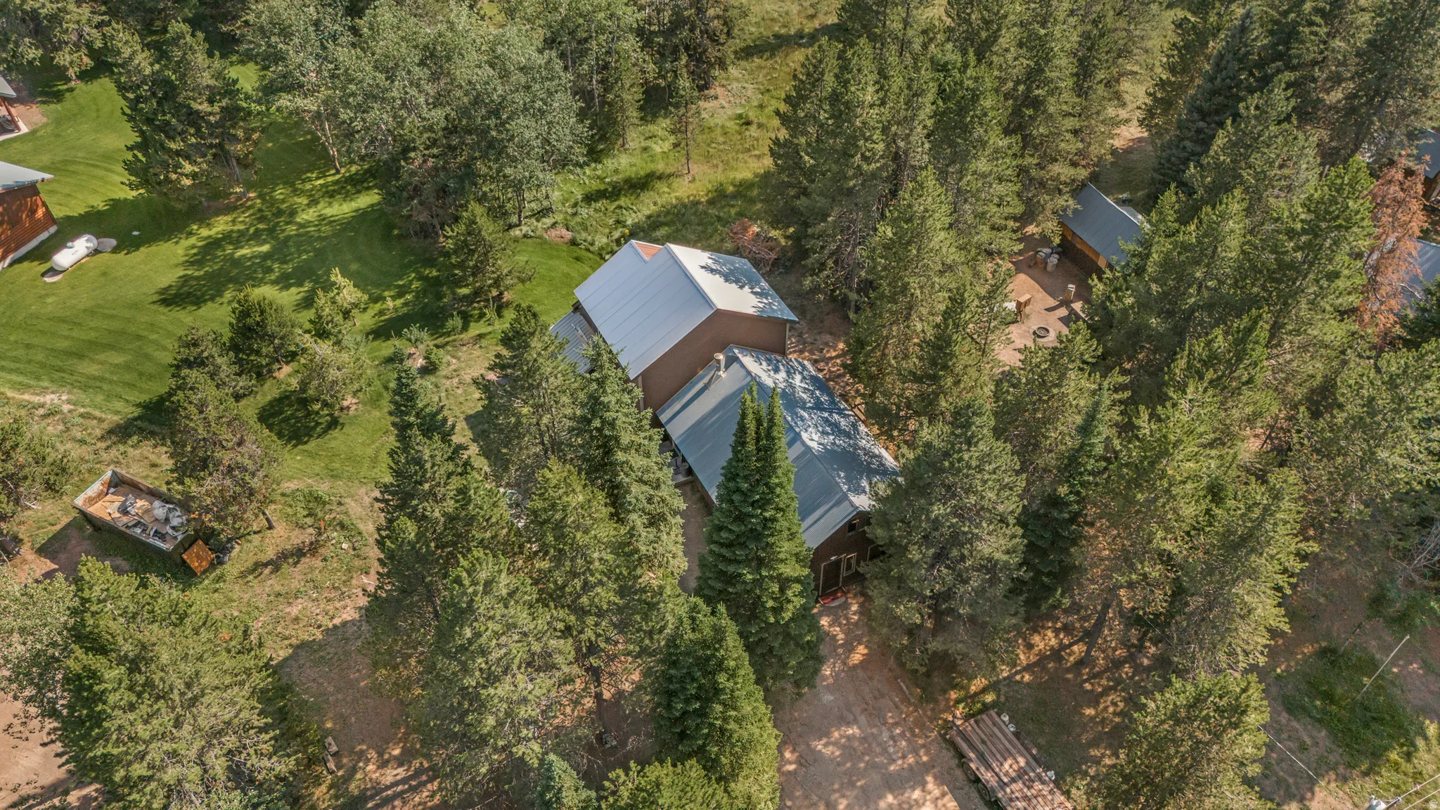 Expansive wooded property featuring multiple structures with metal roofs